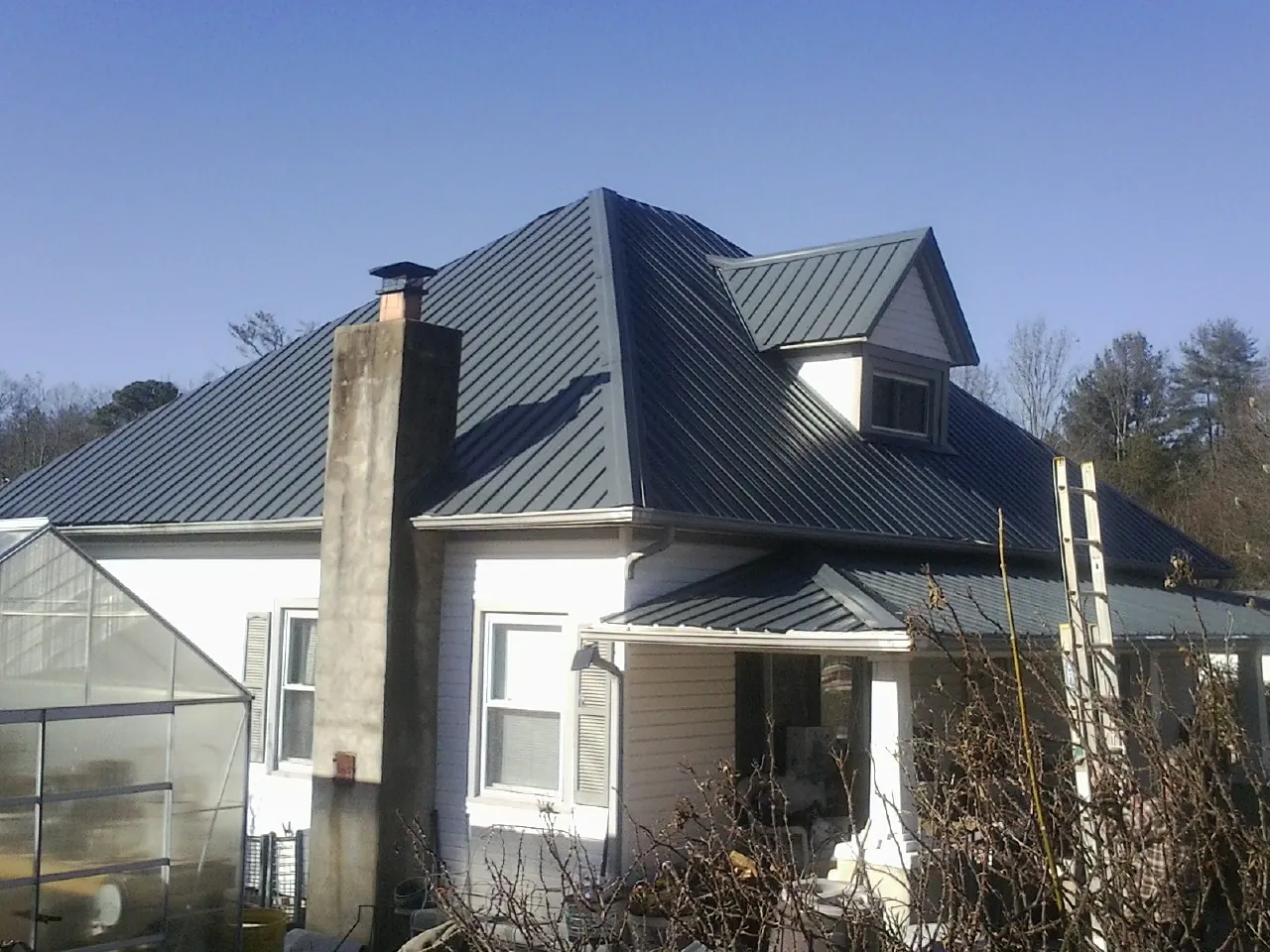 Dark blue standing seam metal roof on a white farmhouse with dormer — Slate & Tile Roof Repair by Roofing Brothers in Rufe