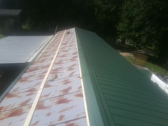 Old rusted panels beside newly installed green metal roofing — Wind Damage Roof Repair by Roofing Brothers in Rufe