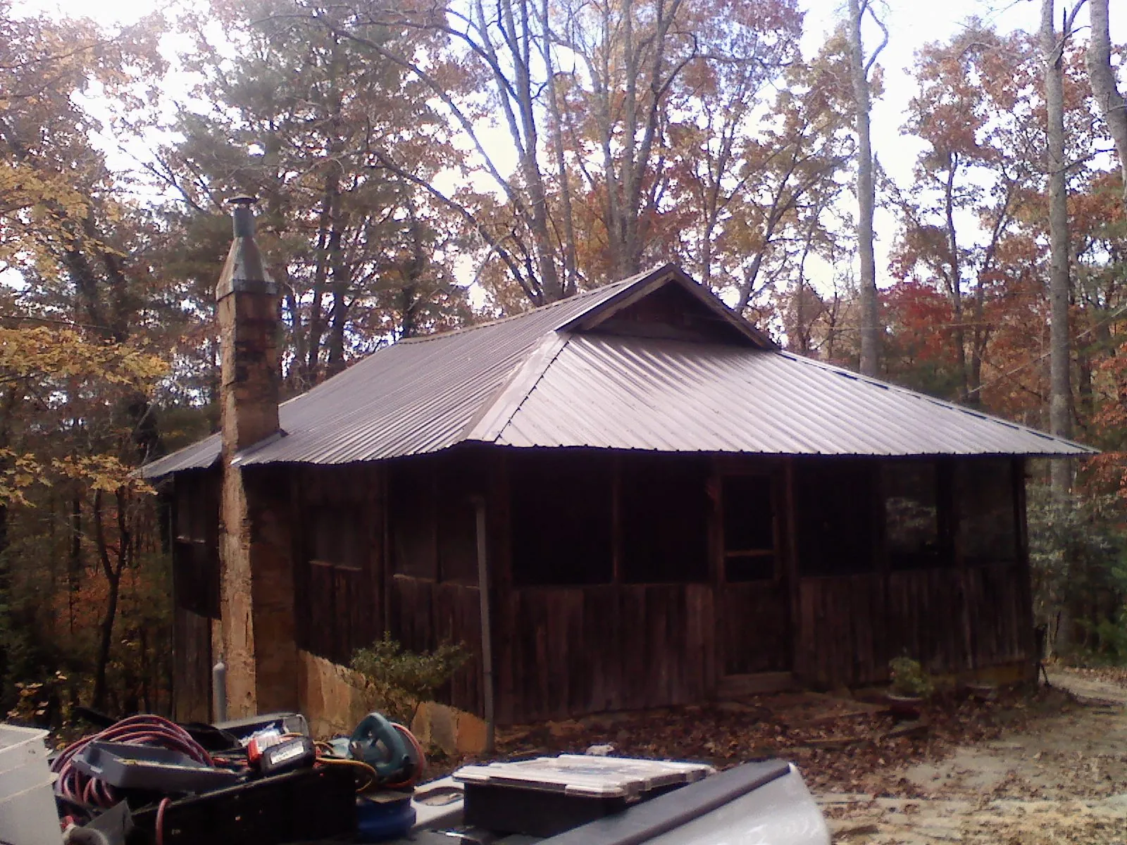 Brown metal hip roof on an old cabin with a stone chimney in Rufe