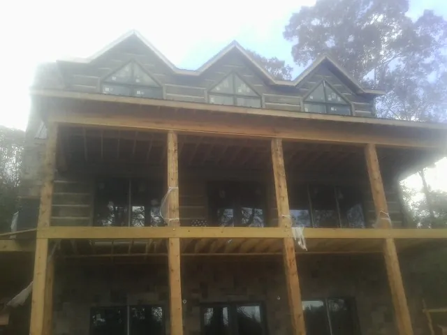 Dormers and porch framing on a large log home under construction — Roof Coating work by our crew in Rufe