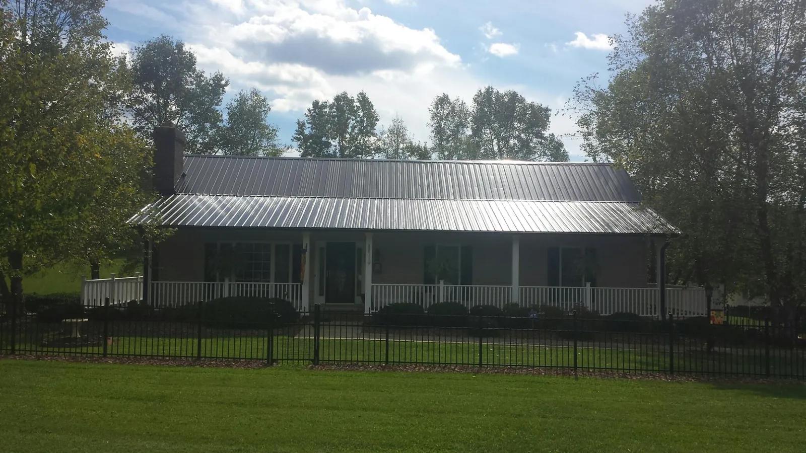 Gray metal roof on a brick ranch with a full width front porch — Gutter Guard Installation work by our crew in Rufe
