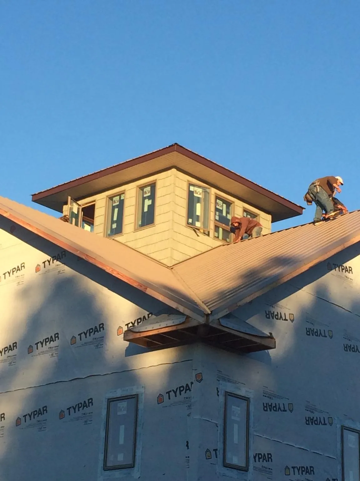 Roofers working around a rooftop cupola on a new metal roof at sunset — Roof Waterproofing in Rufe by Roofing Brothers